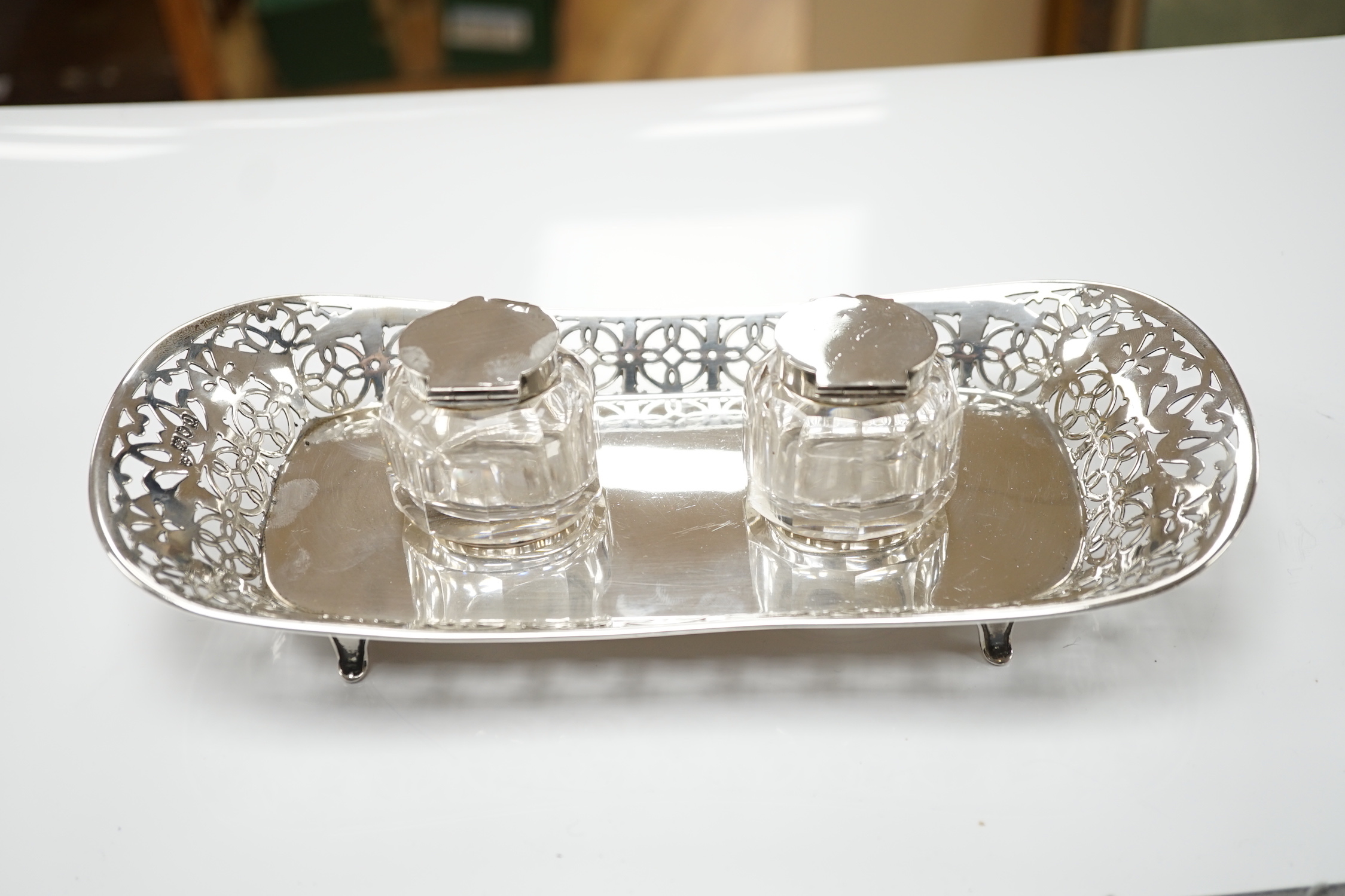 An Edwardian pierced silver inkstand, with two mounted glass wells, on four feet, Haseler Brothers, London, 1909, 26.2cm, 6.5oz.